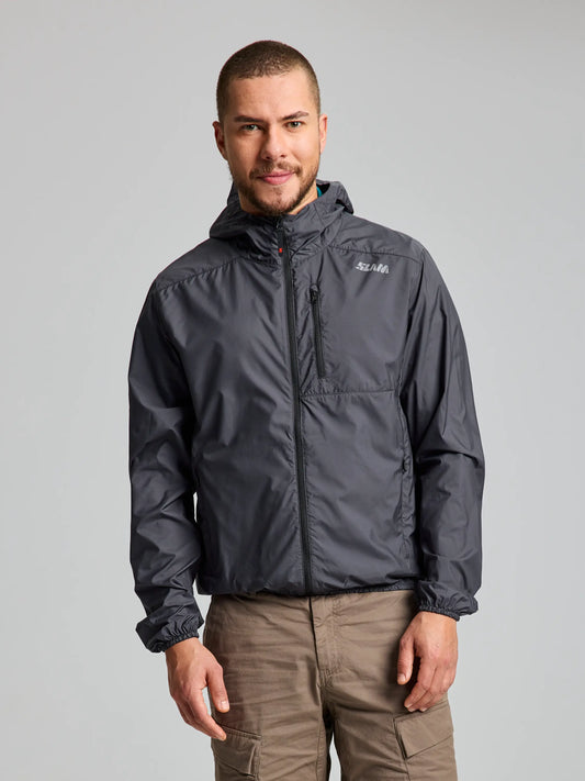 A man with short hair and a beard is wearing a Titanium ACTIVE PACKLITE JACKET from SLAM, paired with beige pants. He stands confidently against a plain light gray background.