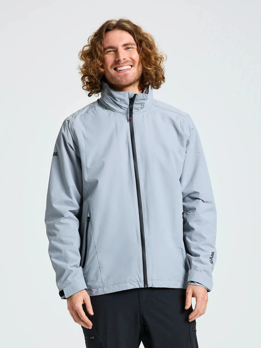 A person with curly hair, wearing the SLAM CREW WARM HOODED JACKET in light gray and black pants, stands against a plain background, smiling and facing the camera.