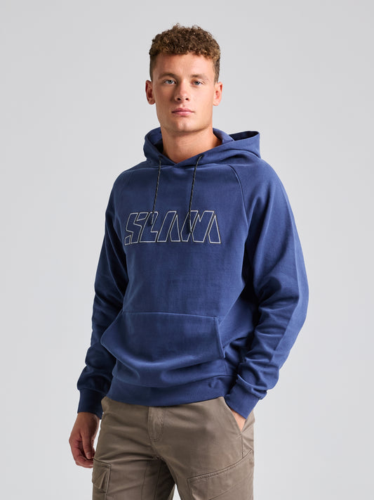 A person wearing the LOGO HOODIE, a men's warm sweatshirt by SLAM, featuring an adjustable hood and displaying the brand's logo in blue, stands against a plain background. They have their hands in their pockets and are wearing khaki pants.