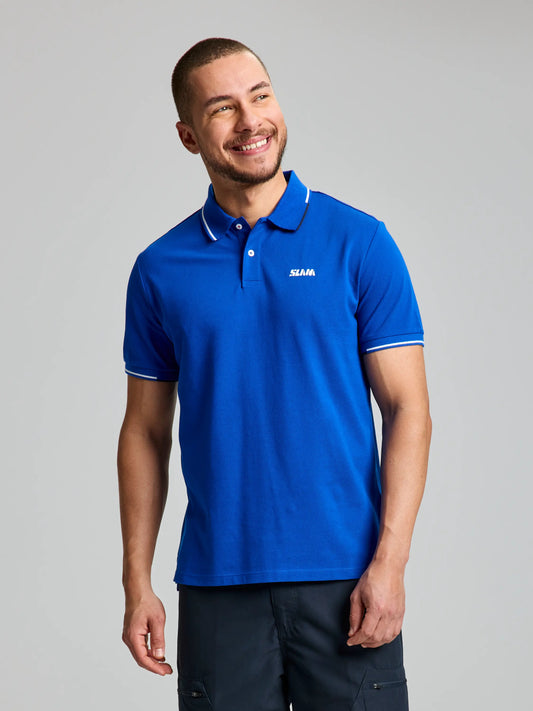 A man with short hair is smiling, wearing the SLAM POLO AEGIR SHORT SLEEVE CL in Olympic Blue. This nautical-style shirt features a ribbed collar and white trim, with the "ISAIA" logo displayed on the chest. He stands against a neutral background with his hands by his sides.