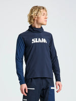 A person with wavy blond hair wears the SLAM OD TECH HOODED T-SHIRT, a navy windproof long-sleeve shirt with bold white 