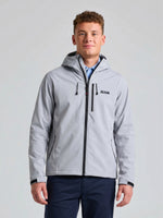 A person stands facing the camera, wearing a light gray SOFTSHELL HOODIE by SLAM, featuring fleece lining, black zippers, and the brand name “SLAM” on the left chest. They are also dressed in dark blue pants, against a plain light-colored background.