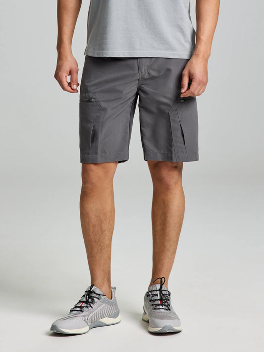 A person wearing a light gray t-shirt and SLAM's ACTIVE CARGO SHORT in titanium stands against a plain background. They are also sporting lightweight gray athletic shoes with white soles and red accents. The water-repellent shorts feature convenient side pockets.