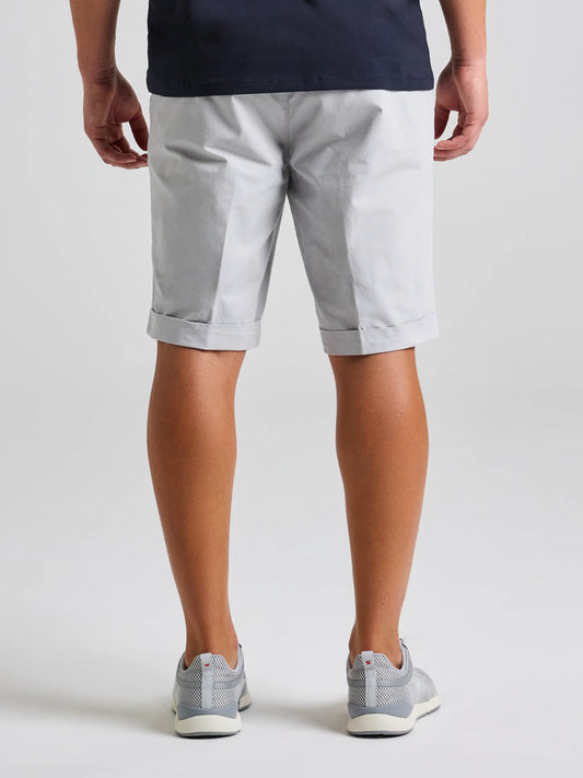 A person faces away from the camera, wearing SLAM DECK LGT CHINO SHORT in light gray cotton twill with a dark shirt and gray sneakers, creating a smart-casual look against a plain light background.