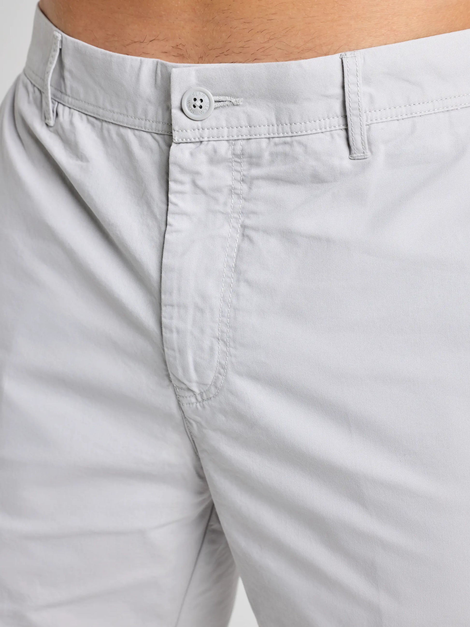 Close-up of a person wearing SLAM DECK LGT CHINO SHORT, highlighting the light gray waistband, button, and zipper. The shorts are made from lightweight fabric, with no other clothing or accessories visible.