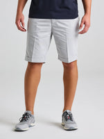 Wearing SLAM's DECK LGT CHINO SHORT in light gray twill cotton, paired with a dark navy tee and gray sneakers, someone stands against a plain background—only the lower half is shown, blending casual and formal styles.