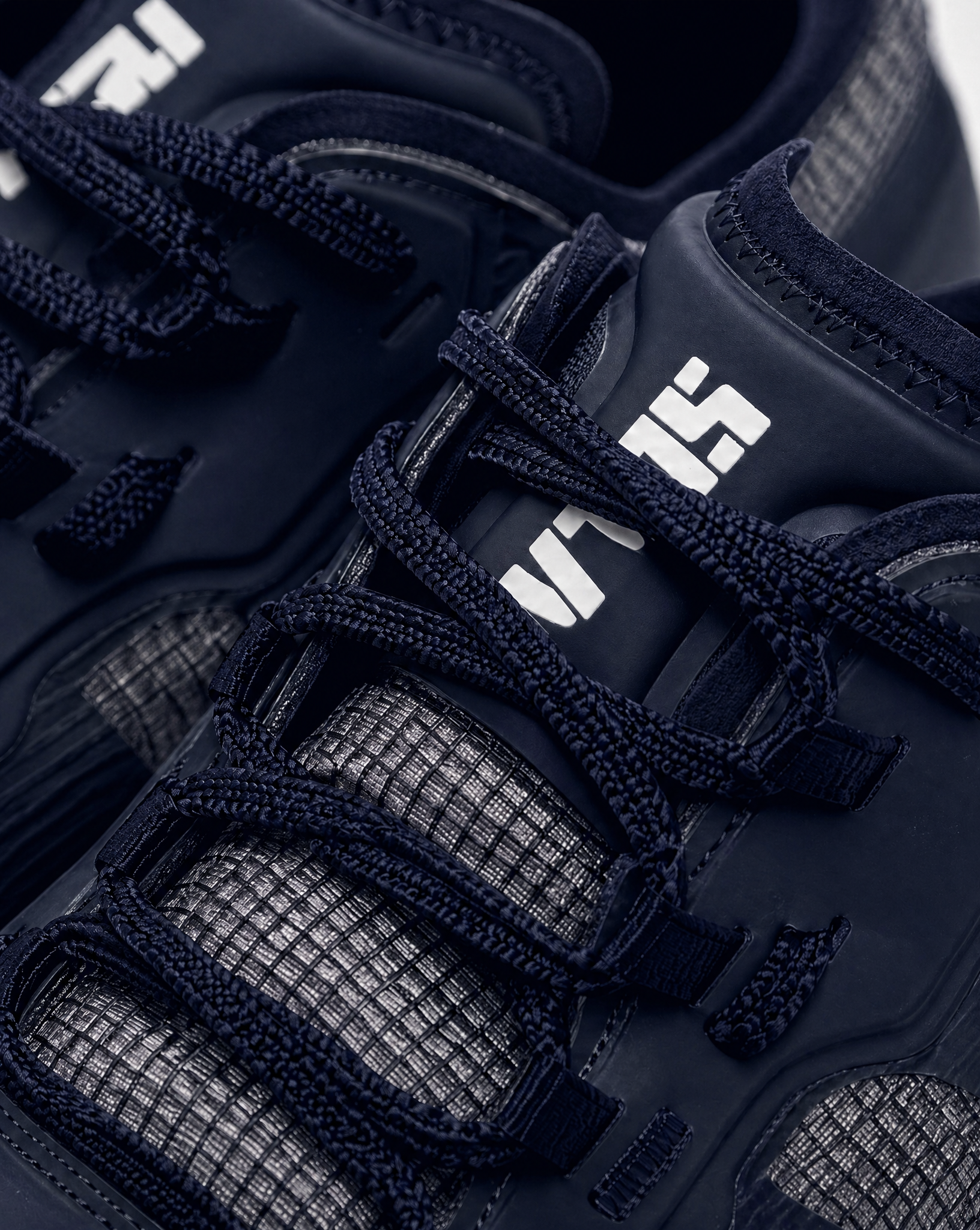 Close-up of SLAM CREW SHOES in dark navy with grid-patterned mesh panels, woven laces, synthetic overlays for support, and a white SLAM logo on the tongue.