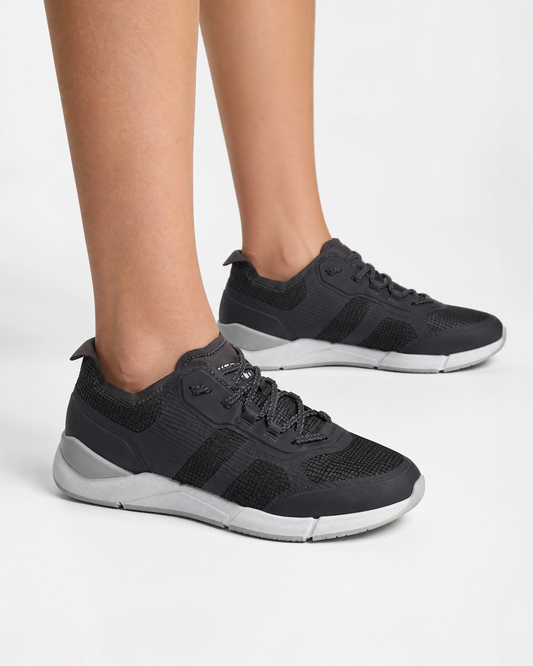 A person wearing SLAM CREW SHOES in DARK TITANIUM with white soles stands on a plain white background, showing only their lower legs and feet.