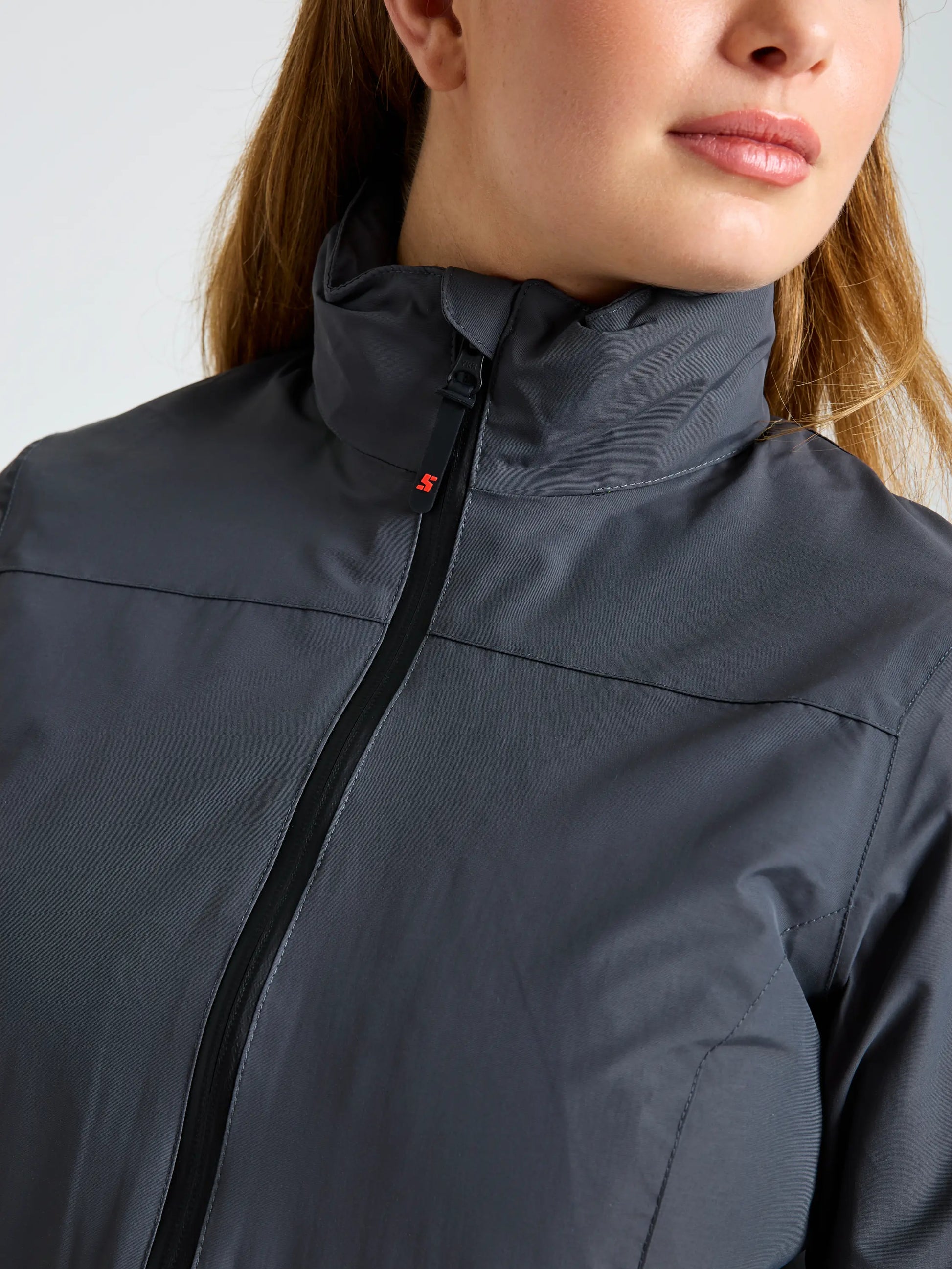 A person is shown from the shoulders up wearing the SLAM CREW WS WARM HOODED JKT in gray, partially zipped with a high collar; only the lower half of their face and neck are visible.