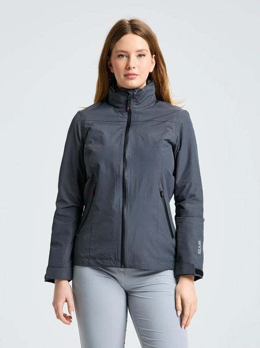 A woman with straight, light brown hair faces forward against a plain light background, wearing light gray pants and the SLAM CREW WS WARM HOODED JKT in gray.