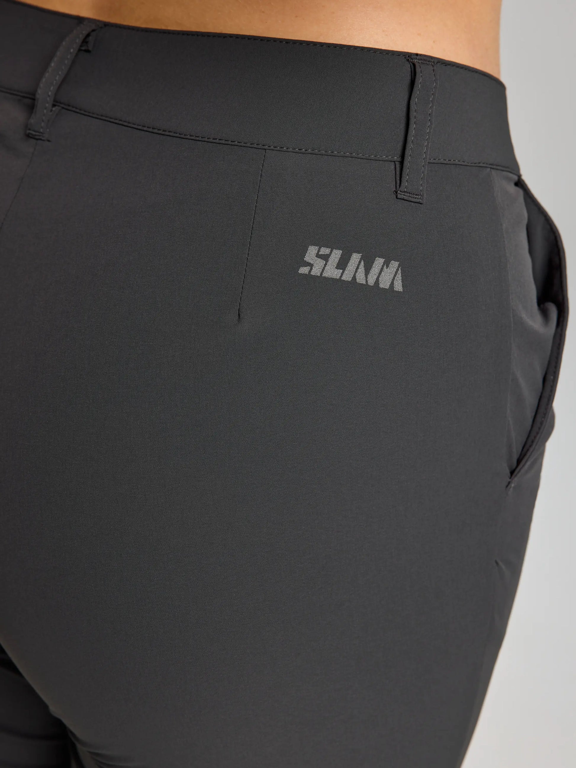 Close-up of SLAM’s WS TECH CHINO PANT, a water-repellent women’s trouser with visible side pocket, belt loop, and “SLAM” in light gray on the upper right waistband for added style.
