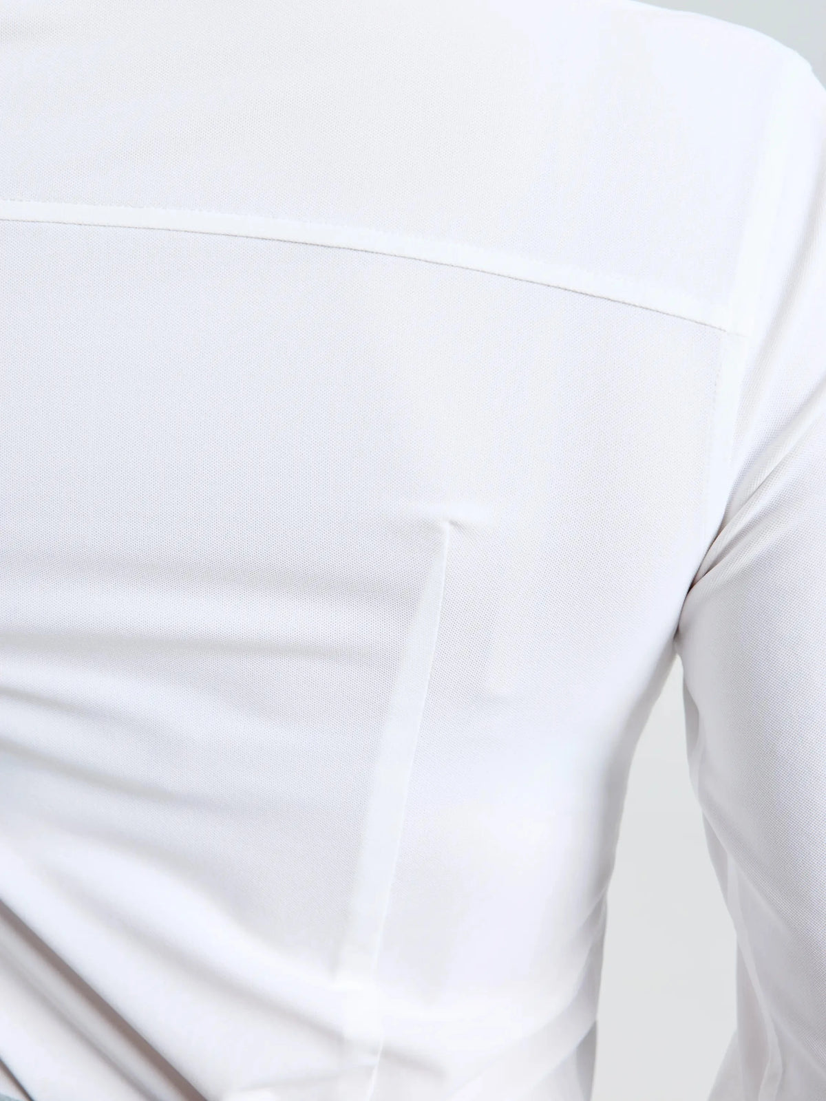 Close-up of the back of the SLAM WS TECH PIQUE SHIRT LS in white, highlighting a horizontal seam across the upper section and subtle vertical stitching details. Crafted for optimal sun protection, this long-sleeve technical shirt features UPF 50+ fabric to keep you safe on bright days.