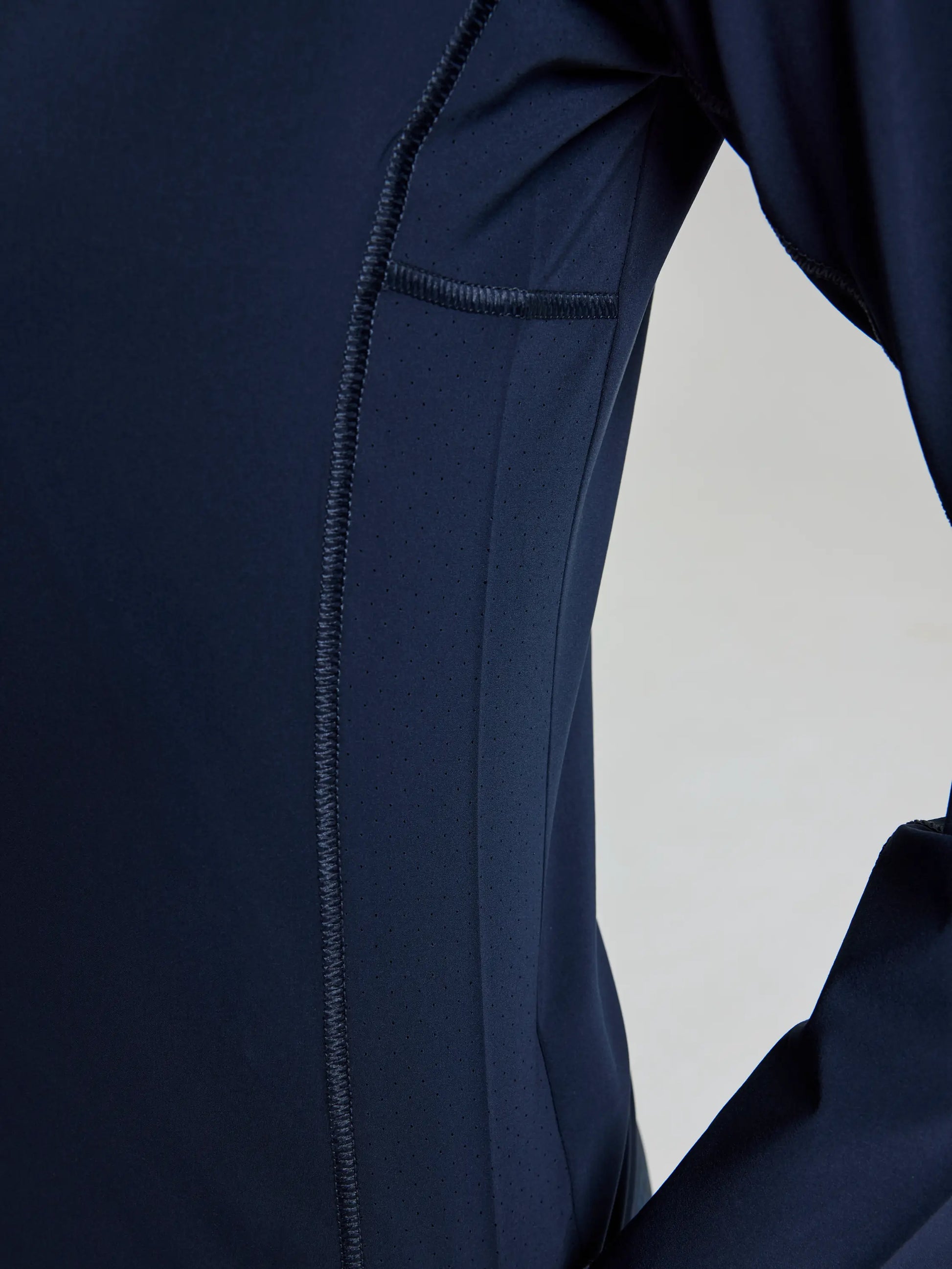 A close-up of the SLAM OD WS TECH T-SHIRT LS in navy blue, highlighting the stitching, side panel, and sleeve details against a light background. This long-sleeve shirt is designed for UV protection.