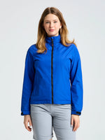 A person stands facing forward, wearing the SLAM WS SAILING JACKET in bright blue and light gray pants, against a plain light background.