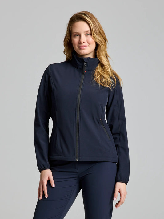 A woman wearing a DARK NAVY ACTIVE WOMAN SOFTSHELL JACKET by SLAM and matching pants stands against a neutral background. Her long, light brown hair frames her face as she looks at the camera with a slight smile. The jacket is designed to be waterproof and windproof, making it perfect for any weather.