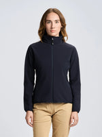 A person with long brown hair is wearing the SLAM ALTURA WS WARM SSHELL JKT in dark navy and beige pants, standing facing forward against a plain light gray background.