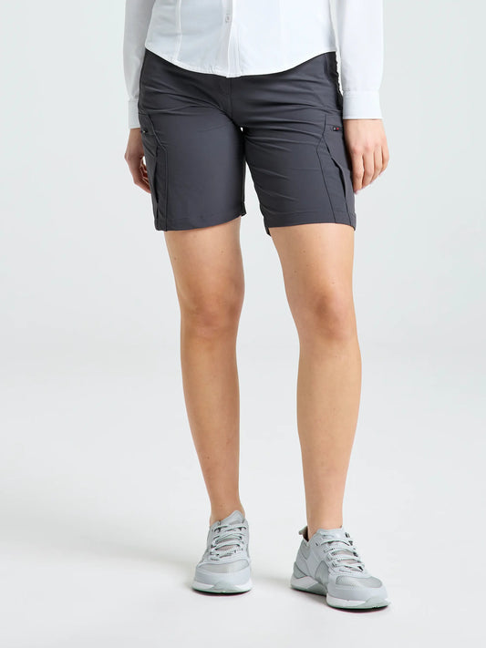 A person wearing a white long-sleeve shirt, SLAM WS TECH CARGO SHORT in dark gray with pockets, and light gray sneakers stands against a plain light background.