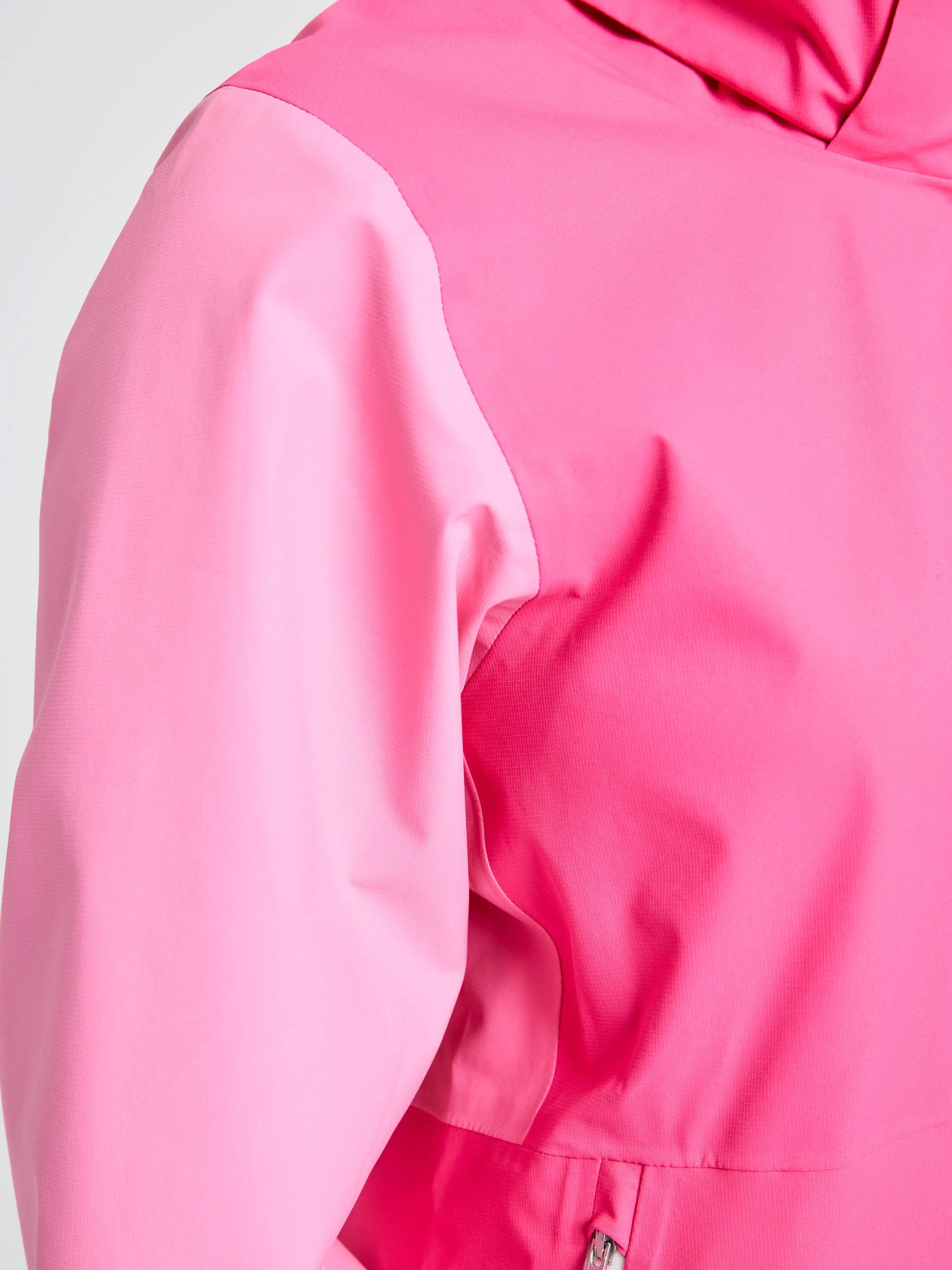 Close-up of the upper sleeve and shoulder area of the SLAM OD WS HOODED JACKET in pink, showing a zipper pocket near the hem. The sleeve displays a slightly different pink shade than the body.