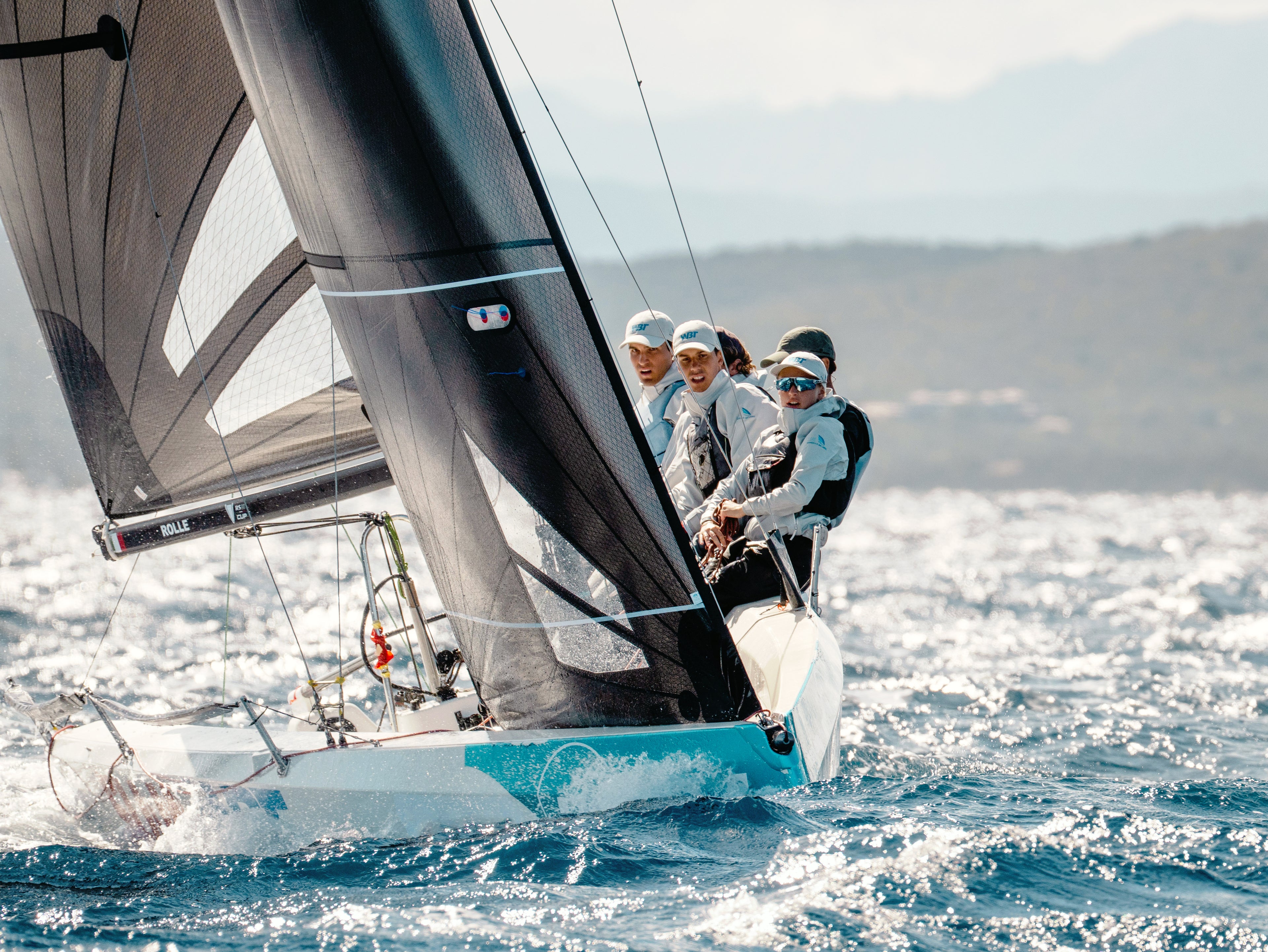 Equipaggio di velisti professionisti in azione durante una regata, con divise tecniche SLAM coordinate