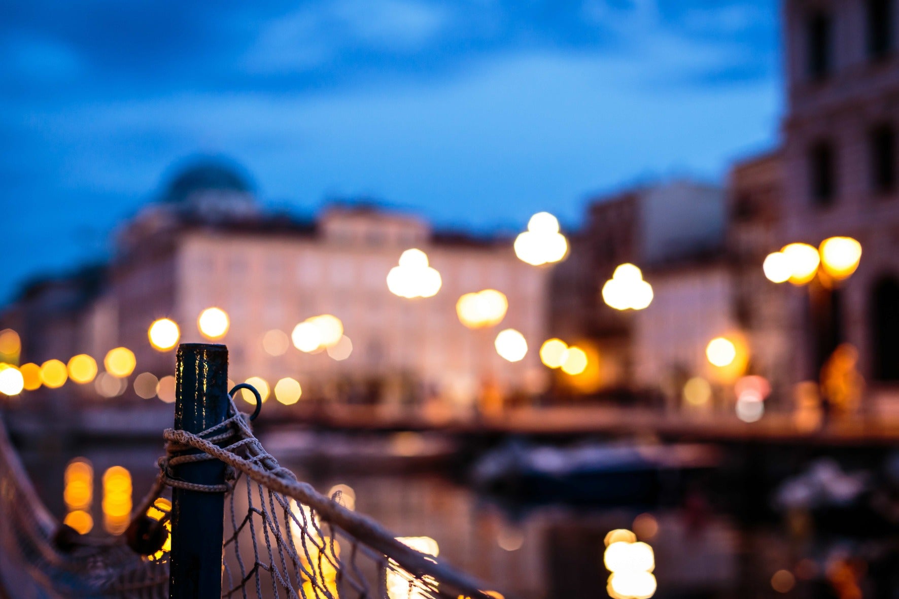 Nautical detail with rope and net in the foreground, lit by warm harbour lights at a winter sunset.