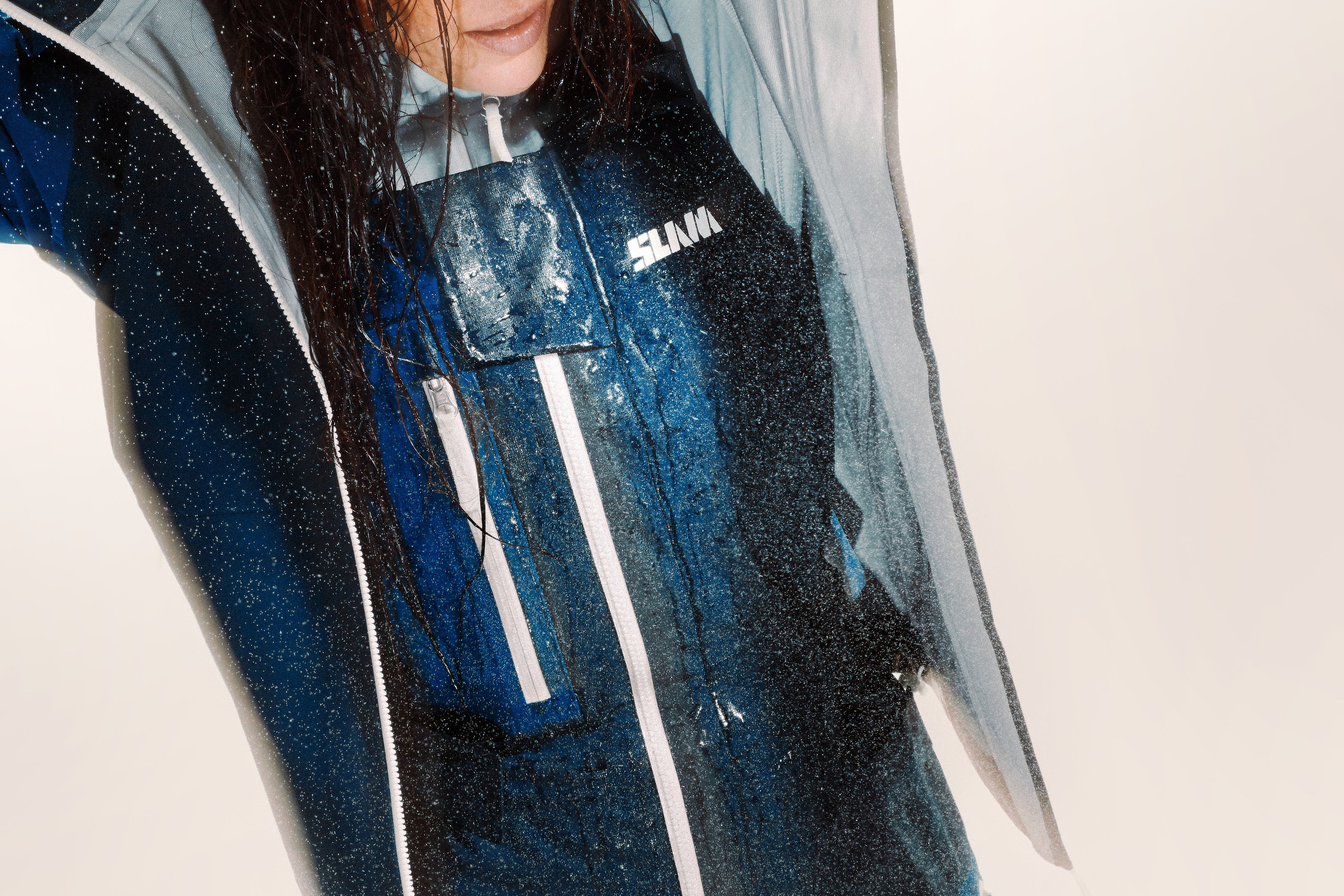 Scatto ravvicinato di una donna con i capelli bagnati che indossa un long john e una giacca blu in tessuto waterproof