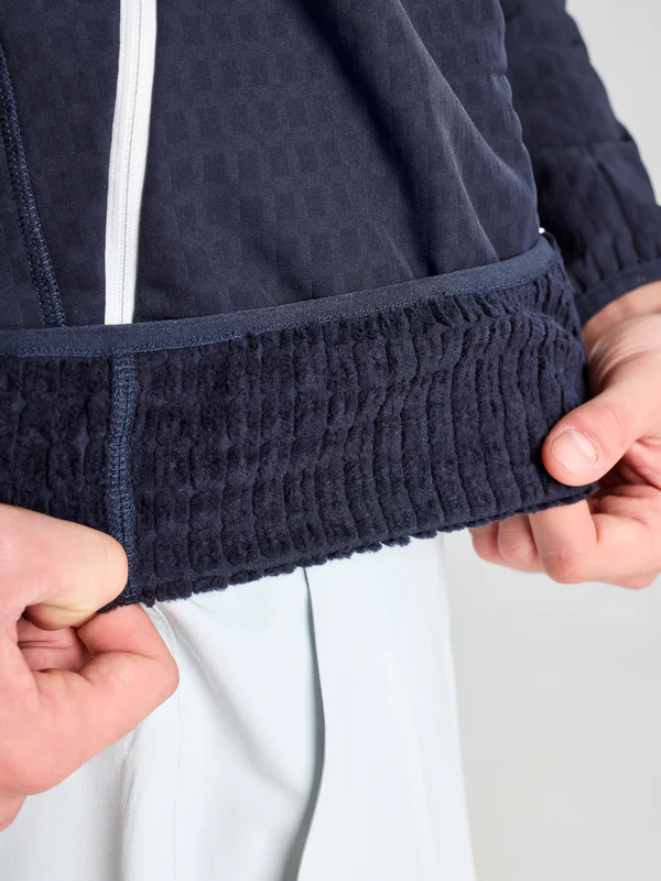 A hand showing the inside of a garment made of grid fleece fabric, featuring a honeycomb weave and excellent thermal insulation