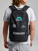 A person in a light gray shirt and shorts is seen from behind carrying the SLAM ETNZ BACKPACK in ETNZ BLACK, featuring 